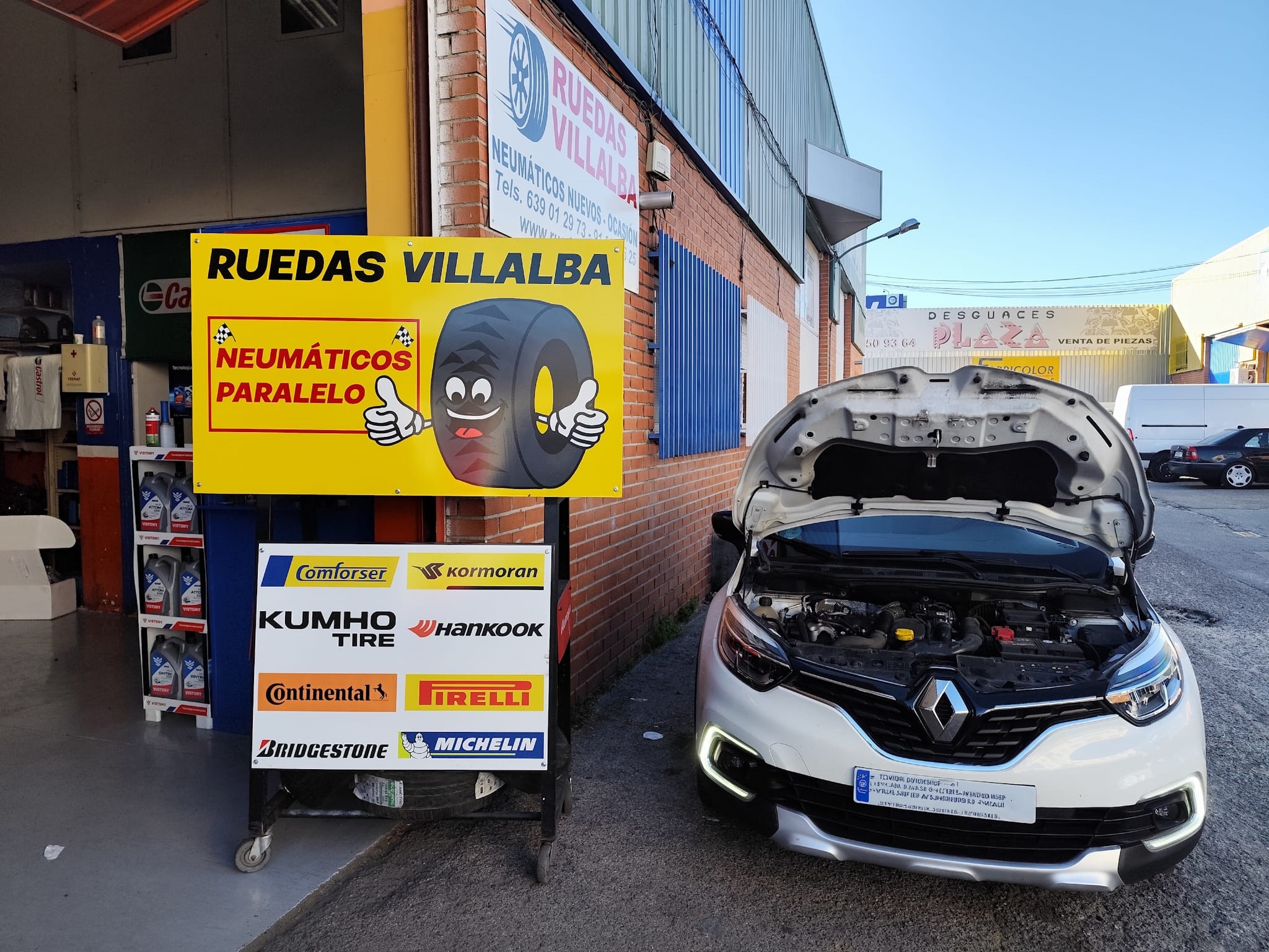 Fachada del taller Ruedas Villalba con cartel de marcas y coche en revisión